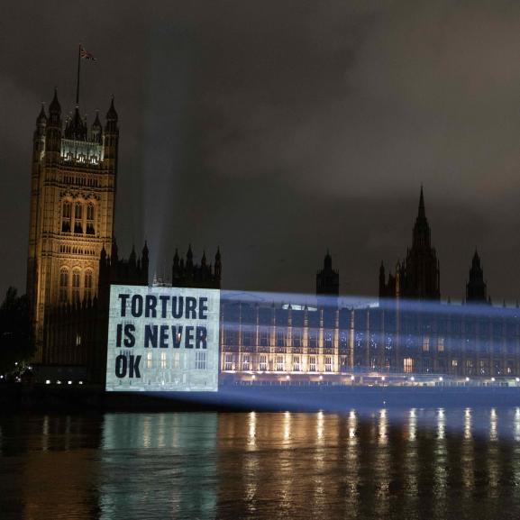 Projection on Parliament reading 'Torture is never ok'