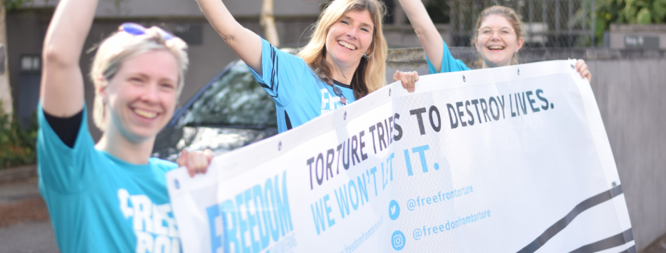 Freedom from Torture staff holding banner