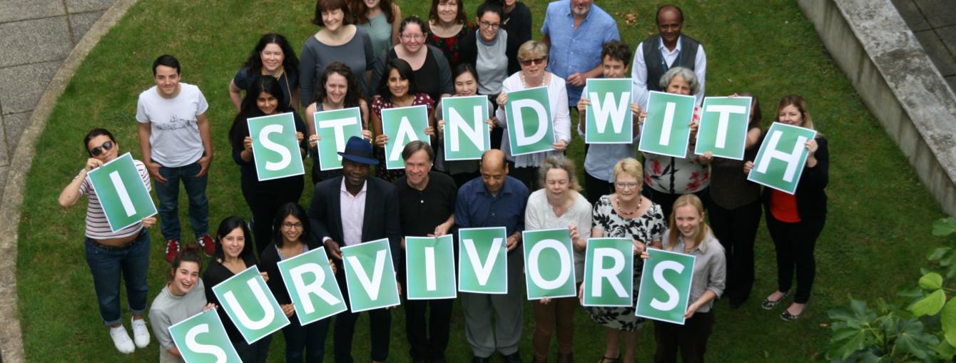 Staff holding a sign saying "I stand with survivors"