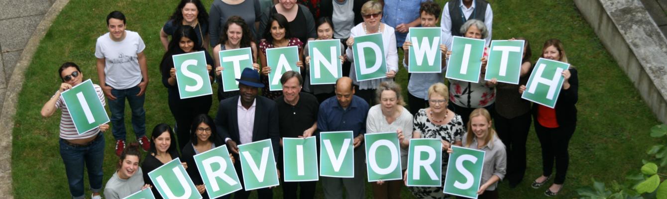 Staff holding a sign saying "I stand with survivors"