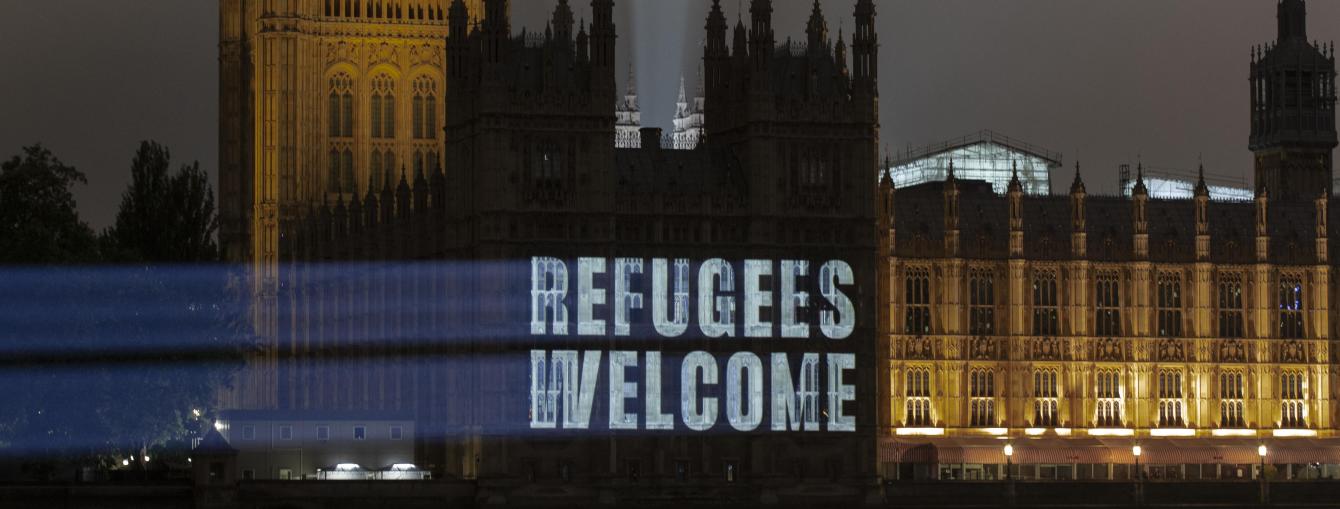 Projection on Parliament reading 'Refugees welcome'