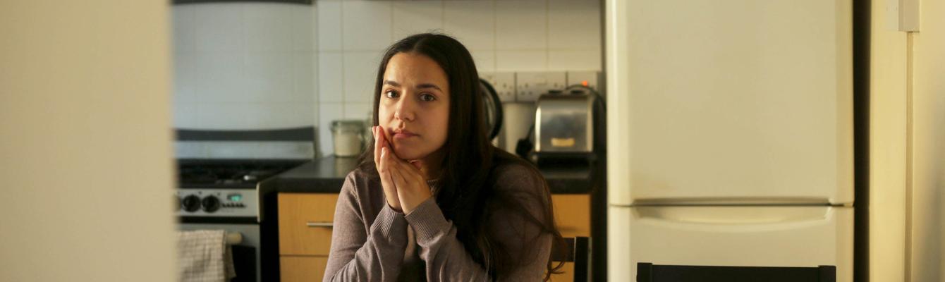 Young woman sitting on table looking into camera