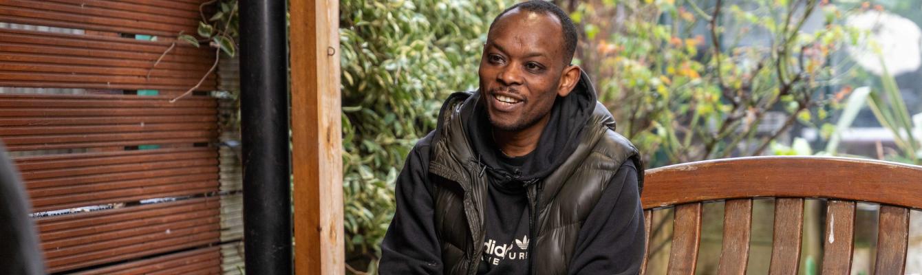 Middle aged man sitting on an outdoor bench smiling