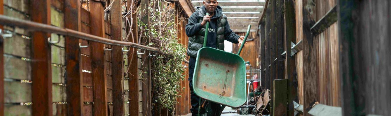 Man carrying wheelbarrow in garden