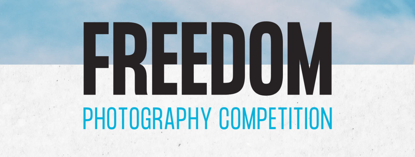 Text reading 'Freedom photography competition'. Freedom is in black and photography competition is in blue with a sky background.