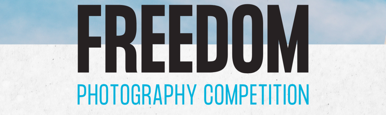 Text reading 'Freedom photography competition'. Freedom is in black and photography competition is in blue with a sky background.