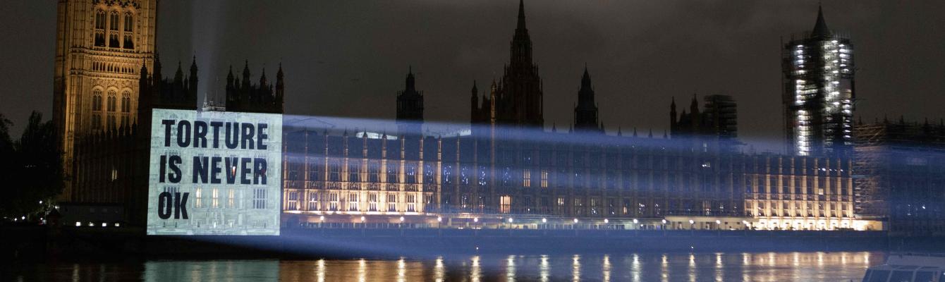 Projection on Parliament reading 'Torture is never ok'