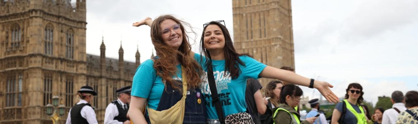 Two young women smiling at the camera outside Parliament