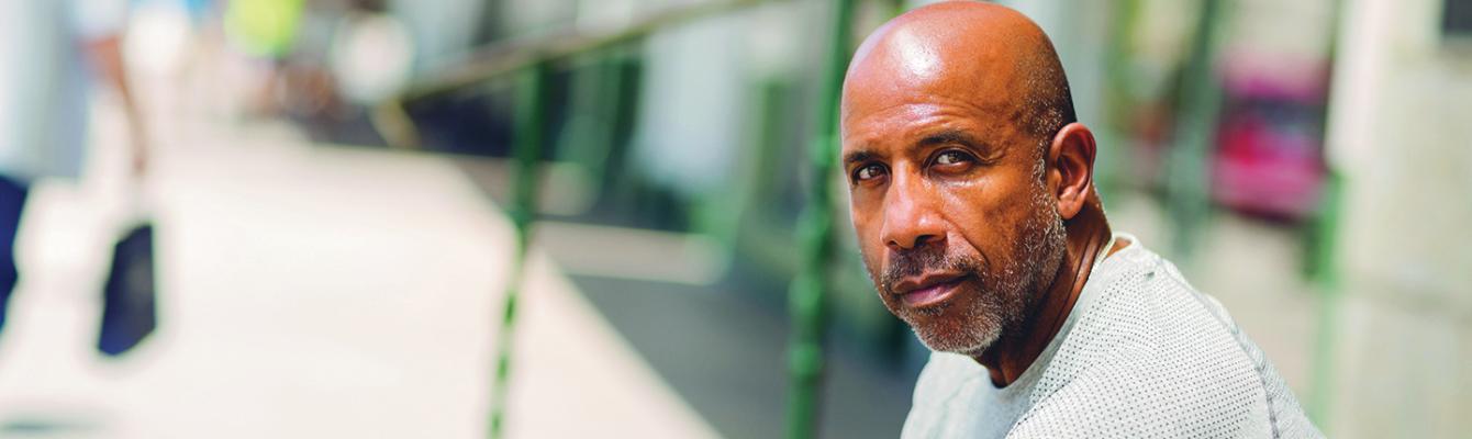 Man looking into camera while sitting outdoors