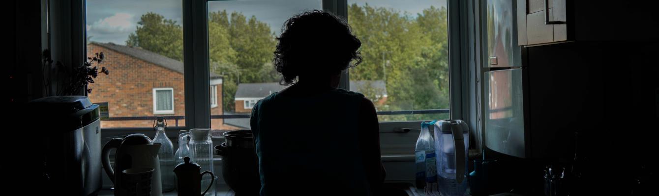 Silhoutte of a female client standing at kitchen sink by window