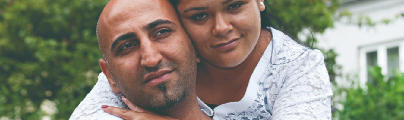 Woman hugging a man. Both look at camera.