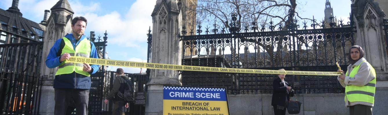 Two peope in Hi-Vis hold 'Crime scene' tape in front of a 'Crime scene' sign outside Parliament