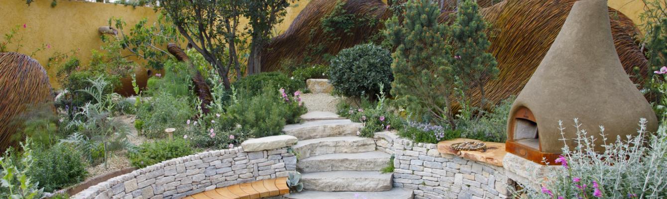Landscape photo of our garden at Chelsea, with a bread oven and seating area