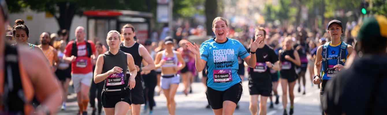 Woman running in a race, smiling at camera