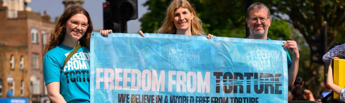 Three people holding a Freedom from Torture