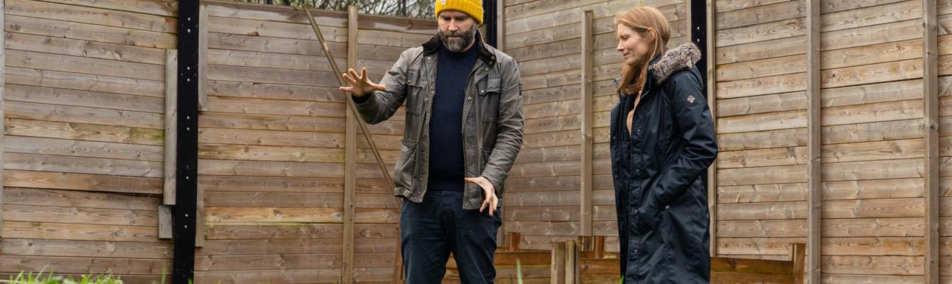 Two people, John and Emma, inspect the garden space