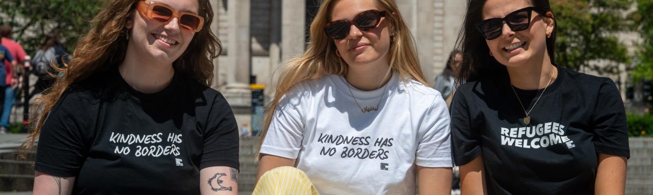 Three women posing with t-shirts