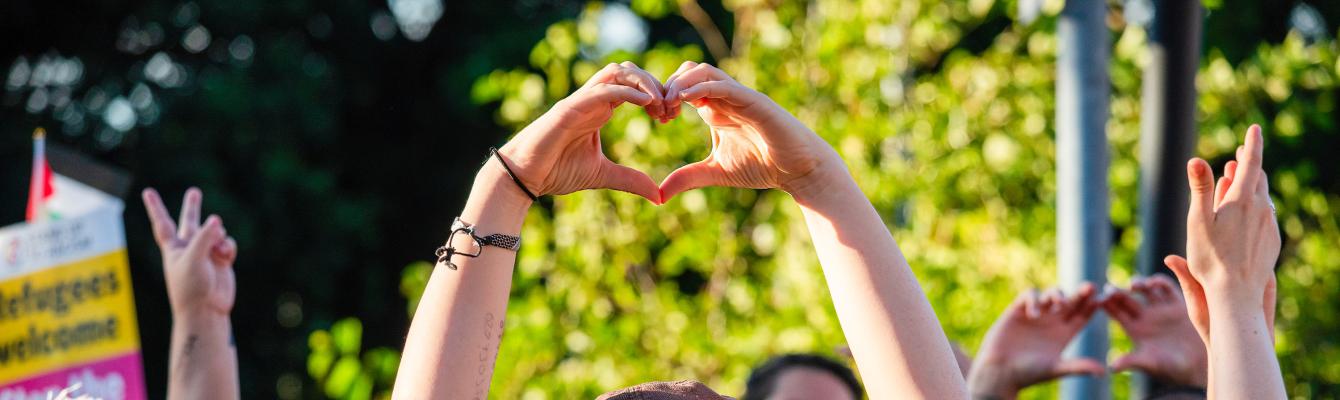 A protester makes a heart with her hands to show her love to asylum seekers