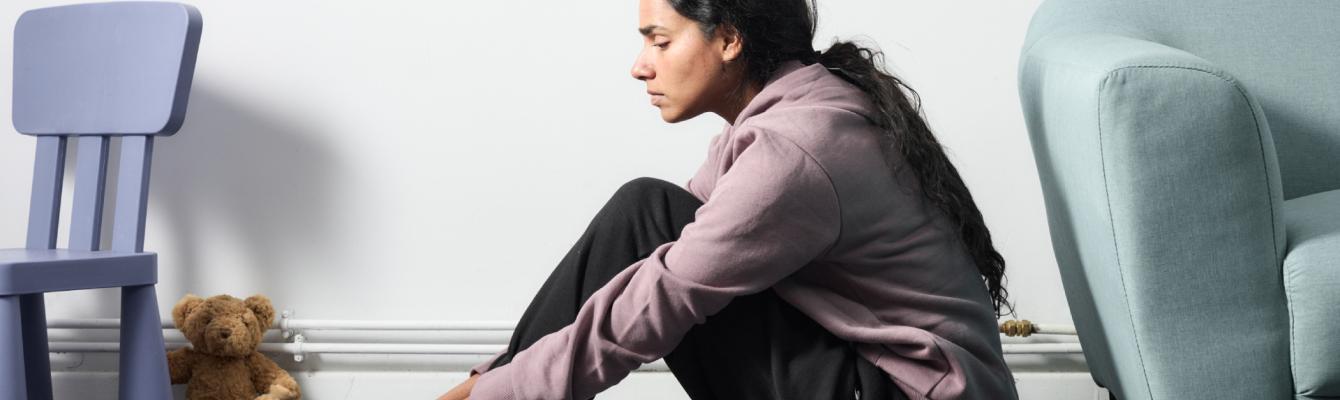 Young South Asian woman sitting on the floor looking sad