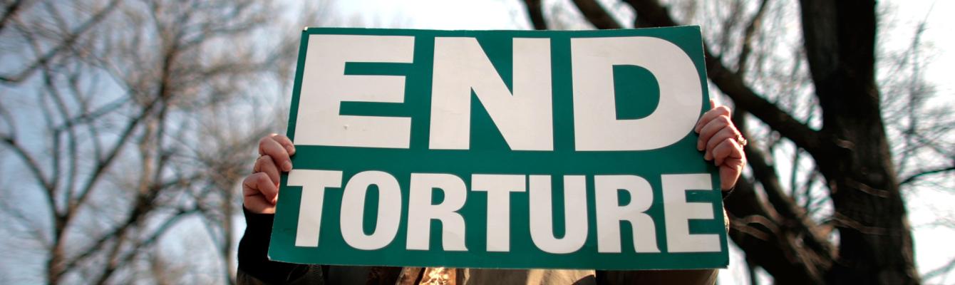 A person holds a sign that reads 'End torture'