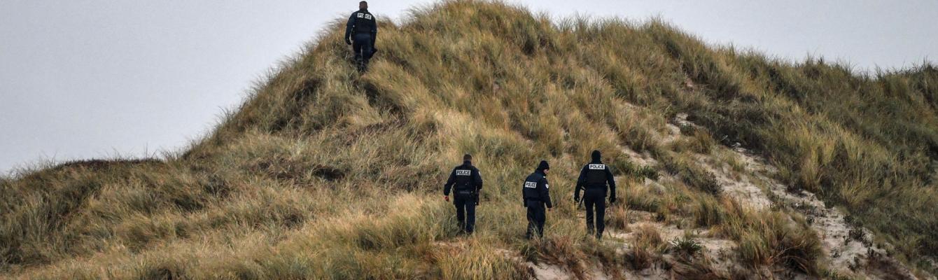 Police officers patrol on the dunes of a beach