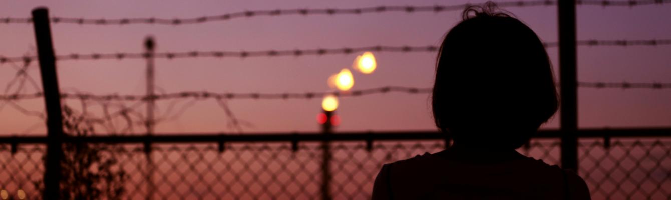 Silhouette of Person in Front of Fence