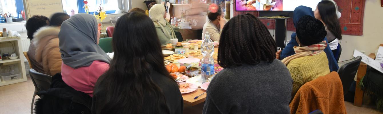 Women sitting around a table, faces concealed