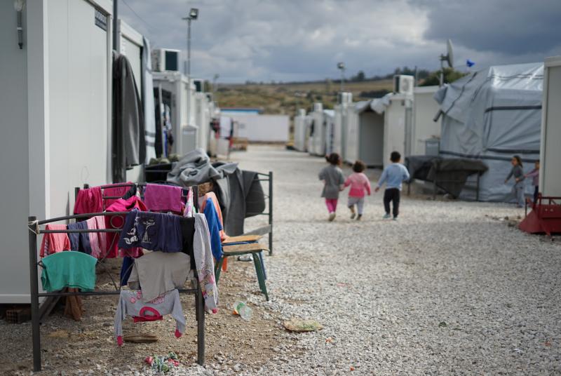 An image of a refugee camp with children in the distance