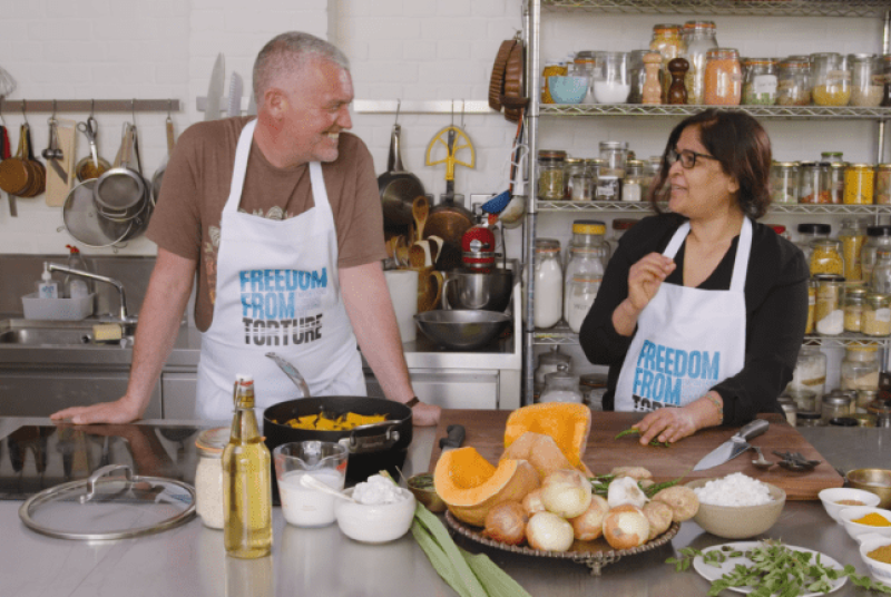 Paul and Nafa in a kitchen smiling at each other