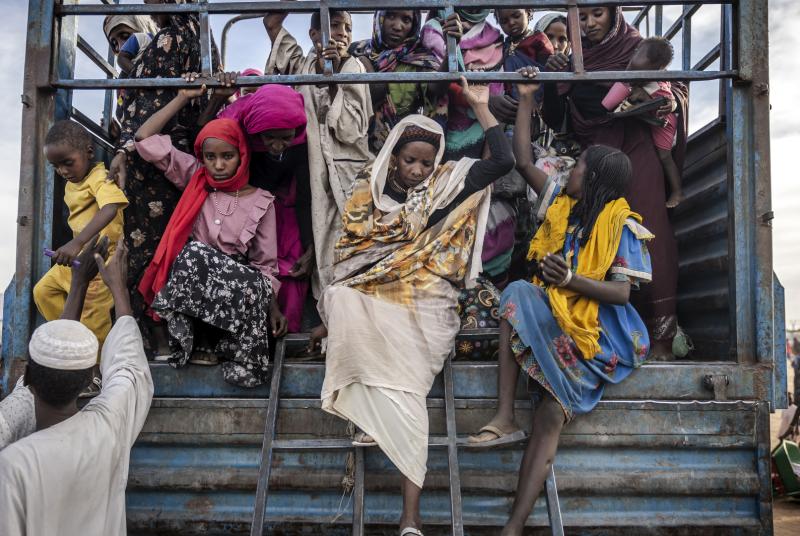 Sudanese refugees get off a truck loaded with families arriving at a Transit Centre