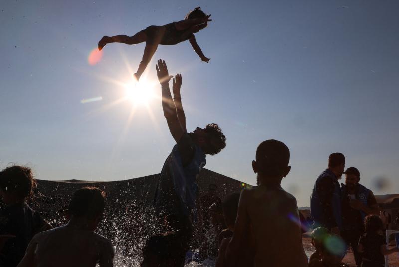 Silhoutte of a man throwing a child in the air while bathing