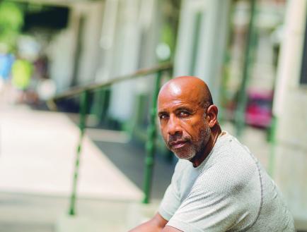 Man looking into camera while sitting outdoors