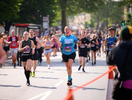 Woman running in a race, smiling at camera