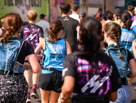 the back of two women wearing freedom from torture running vests in a crowd of runners