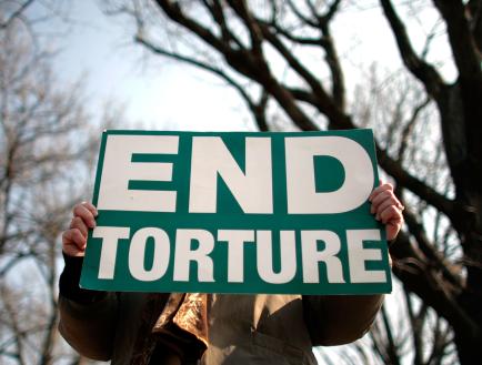 A person holds a sign that reads 'End torture'