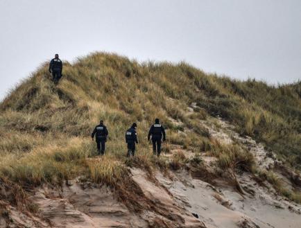 Police officers patrol on the dunes of a beach