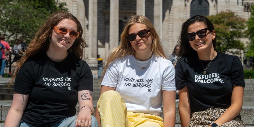 Three women posing with t-shirts