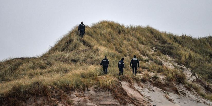 Police officers patrol on the dunes of a beach
