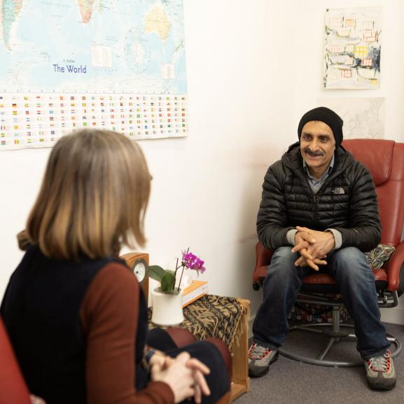 A client and a therapist sit facing each other having a one-to-one therapy session.