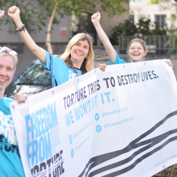 Freedom from Torture staff holding banner