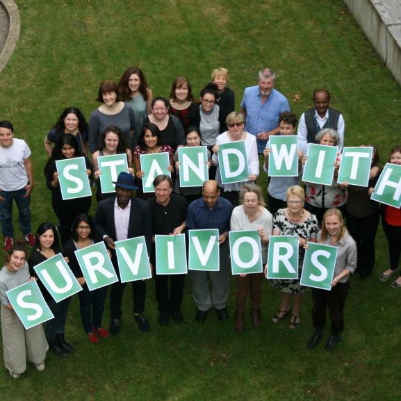 Staff holding a sign saying "I stand with survivors"