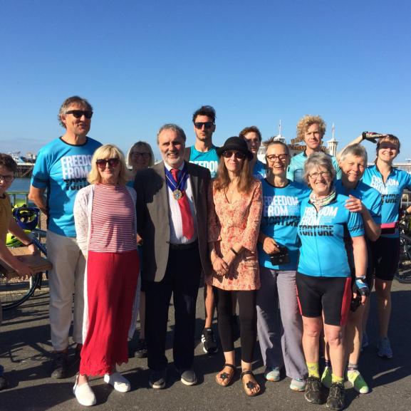 Group photo of people by the beach in Freedom from Torture t-shirt