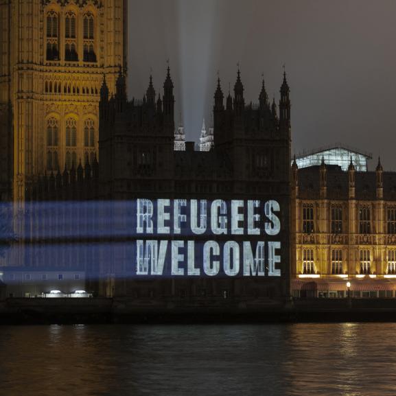 Projection on Parliament reading 'Refugees welcome'