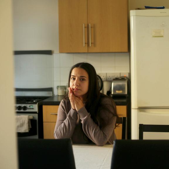 Young woman sitting on table looking into camera