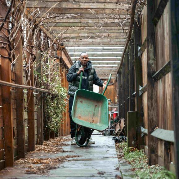 Man carrying wheelbarrow in garden