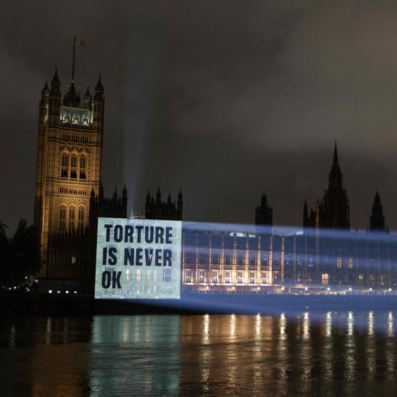 Projection on Parliament reading 'Torture is never ok'