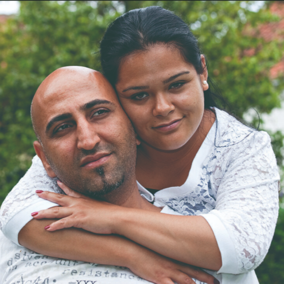 Woman hugging a man. Both look at camera.