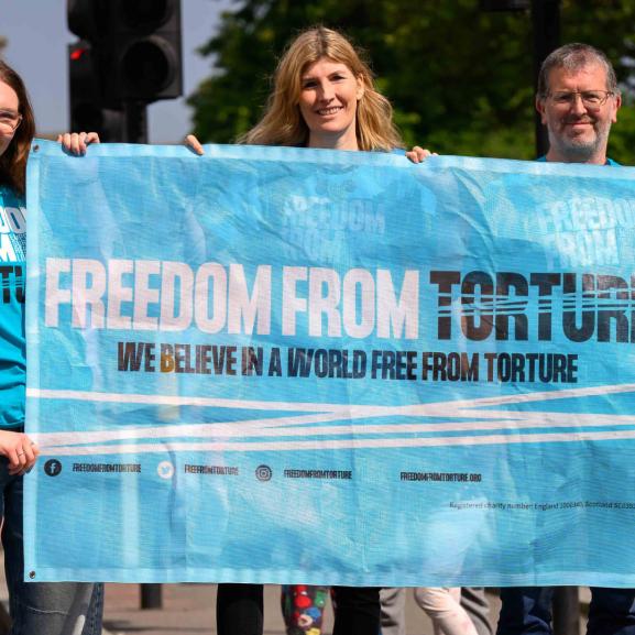 Three people holding a Freedom from Torture