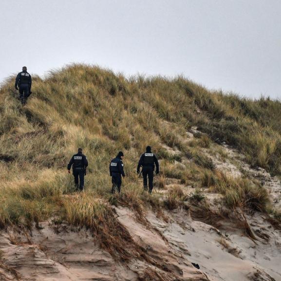 Police officers patrol on the dunes of a beach