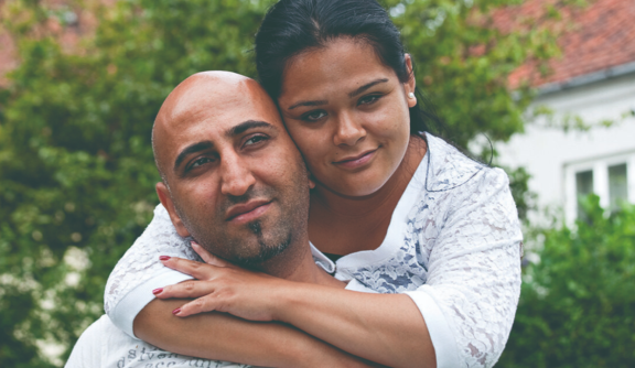 Woman hugging a man. Both look at camera.